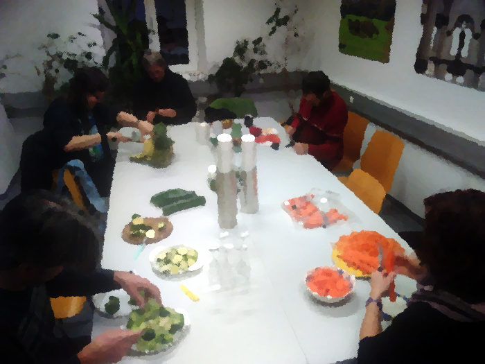 Leute um Tisch, die Gemüse schneiden