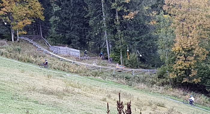 Blick auf Sommerrodelbahn, mit Mountainbikern an Schlepplift